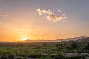 aerial photography of green grass field surrounded with mountain during sunset