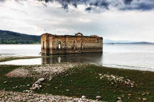 gray and brown building on body of water under cloudy sky during daytime