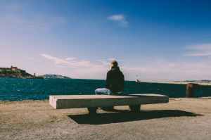 person wearing blue jeans sitting on bench