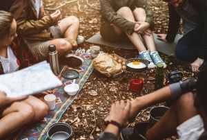 group of people sitting on ground while cooking egg