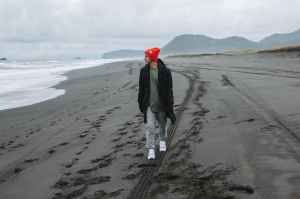 male tourist walking along empty beach and admiring view on ocean